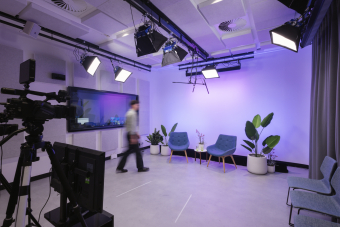 Studio with purple lighting, two blue chairs, and decorative plants.